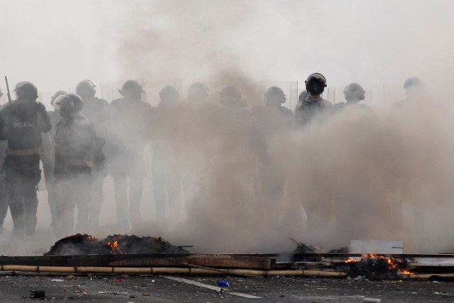 Venezuela's national police officers stand amidst teargas during an opposition protest at Prados del Este's highway in Caracas