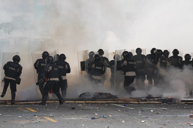 Venezuela's national police officers stand amidst teargas during an opposition protest at Prados del Este's highway in Caracas