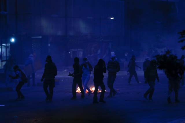 Anti-government protesters wait for police during riots in Caracas