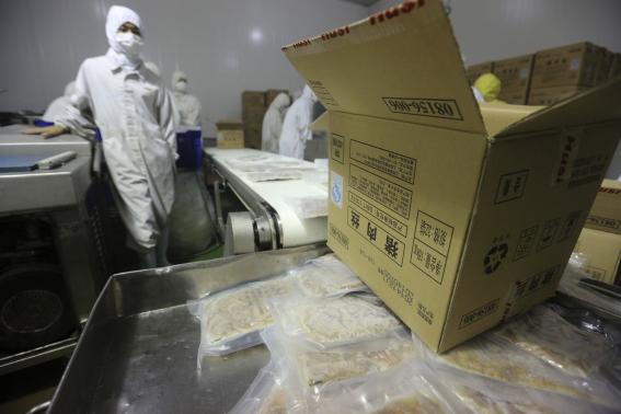 Employees work at a production line prior to a seizure at the Husi Food factory in Shanghai