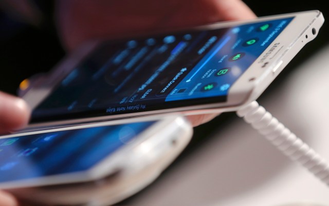 A visitor holds a new Samsung Galaxy Note Edge smartphone next to another device at the Unpacked 2014 Episode 2 event ahead of the IFA Electronics show in Berlin