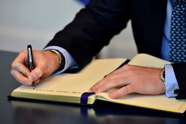 Britain's Prince Harry signs a book of condolence at the French embassy in London