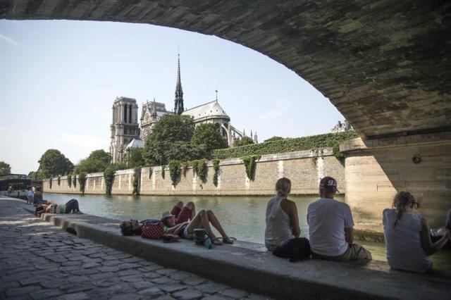 Varias personas descansan en la orilla del Sena, junto a Notre Dame en París, Francia hoy 1 de julio de 2015 durante la ola de calor que asola la capital francesa. EFE/Etienne Laurent