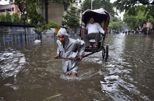 Un hombre transporta a un cliente en un carrito por una calle inundada tras las intensas lluvias caídas en Kolkata, India, el 1 de agosto de 2015. Al parecer 21 personas perdieron la vida debido a un alud de lodo, tierra y piedras ocasionado por las lluvias monzónicas en la aldea de Joumol, estado de Manipur, noreste de India, según las autoridades. (Vía AP Foto/Swapan Mahapatra/Press Trust of India)