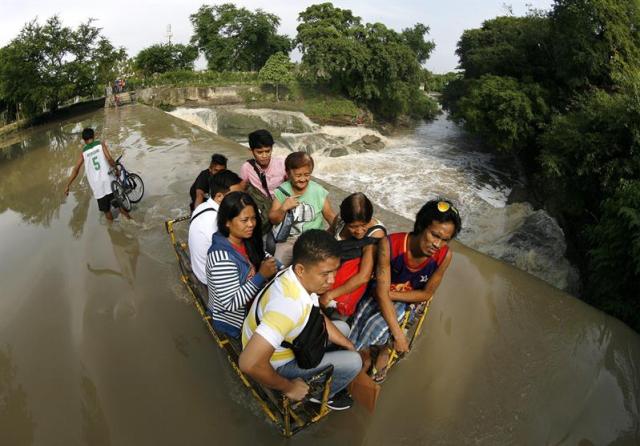 Varias personas cruzan un río desbordado en Las Pinas a las afueras de Manila (Filipinas) hoy 6 de agosto de 2015. Al menos siete personas han muerto y otras tres permanecen desaparecidas en las inundaciones. Además, el tifón Soudelor, el más intenso de 2015, se acerca a las islas de Batanes, en el extremo norte de Filipinas, por lo que las autoridades han activado la alerta meteorológica en la zona, informaron hoy fuentes gubernamentales. Aunque no se espera que el tifón llegue a las costas filipinas, PAGASA activó en Batanes el nivel de alerta 1, de un máximo de 4, lo que indica la posibilidad de vientos desde 30 a 60 kilómetros por hora y precipitaciones moderadas en los próximos días, que podrían causar inundaciones. Los expertos predicen que el tifón, bautizado con el nombre de Hanna por las autoridades locales, estará a 355 kilómetros de Itbayat, Batanes, el próximo sábado, y habrá salido de aguas filipinas el domingo en dirección hacia Taiwán y China. EFE/Francis R. Malasig