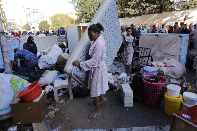 Dos mujeres cargan con un colchón después de ser desahuciadas de su apartamento en Hillbrow, Johannesburgo (Sudáfrica), hoy, 12 de agosto de 2015. El propietario del bloque de edificios obtuvo una orden judicial para desalojar a 1.500 personas, muchas de las cuales afirman no haber recibido ningún aviso del desahucio. EFE/KIM LUDBROOK