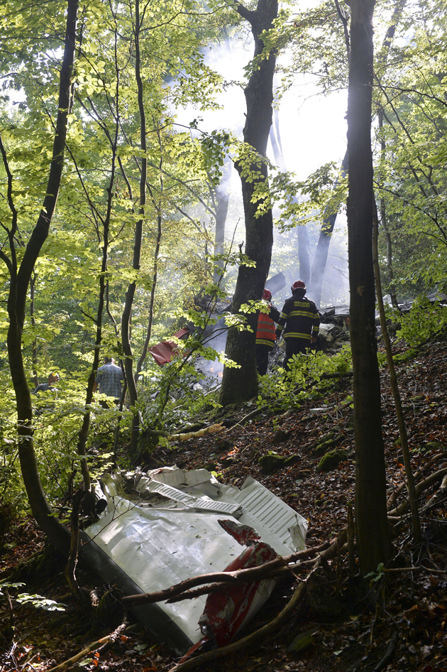 Firefighters inspect the crash site of two sport planes near the village of Cerveny Kamen, Slovakia, August 20, 2015. The death toll from the mid-air collision between the two sport planes over western Slovakia has risen to seven, according to a fire department spokesman.    REUTERS/Radovan Stoklasa