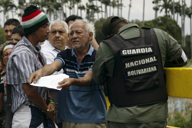 A man shows a paper to a Venezuelan soldier, while he waits to try to cross the Simon Bolivar international bridge, on the border with Colombia, at San Antonio in Tachira state, Venezuela August 22, 2015. Venezuela's closure of two border crossings with Colombia hurts innocent people, Colombia's President Juan Manuel Santos said on Saturday, adding that he hoped to speak to his Venezuelan counterpart Nicolas Maduro to find a solution. Maduro closed the crossings on Wednesday after a shootout between smugglers and troops left three soldiers wounded. He declared a 60-day state of emergency in five border municipalities on Friday. REUTERS/Stringer