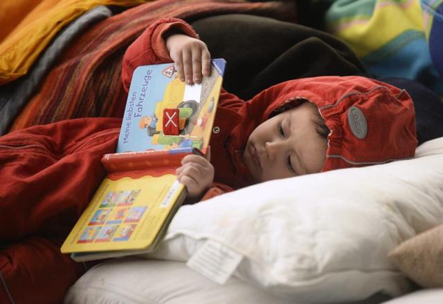 Un niño lee un libro en un refugio temporal en Wiesen (Austria) hoy, 21 de septiembre de 2015. Las autoridades de Hungría interceptaron entre el viernes y el domingo en total a 18.757 refugiados por cruce ilegal de la frontera, informó hoy la policía local. La gran mayoría de los refugiados entró en el país desde Croacia y fueron luego trasladados por las autoridades húngaras hasta cerca de la frontera austríaca, desde donde siguieron a Austria. EFE/Roland Schlager