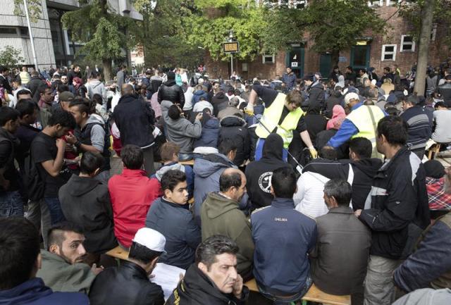 Refugiados permanecen sentados a la entrada de la Oficina Estatal de Salud y Bienestar de Berlín hoy, 23 de Septiembre de 2015, a la espera de que les asignen un refugio para dormir tras cumplimentar su registro. EFE/JOERG CARSTENSEN