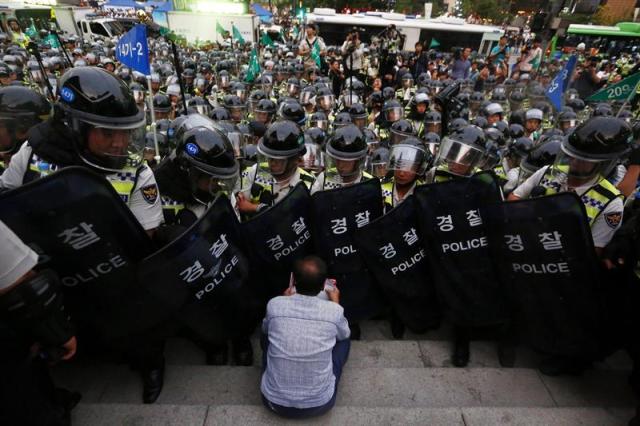 Un miembros de la Confederación de Sindicatos de Corea (CSC) se ve rodeado por los agentes antidisturbios durante una protesta para demandar mejoras en la política laboral del Gobierno así como para pedir la dimisión del presidente surcoreano, Park Geun-Hye, en Seúl (Corea del Sur), hoy, 23 de septiembre de 2015. EFE/Jeon Heon-Kyun