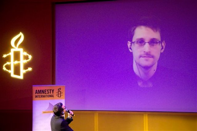 Fotografía de archivo del 10 de diciembre de 2014 muestra al ex contratista de la Agencia de Seguridad Nacional de Estados Unidos Edward Snowden, quien está en Moscú, en una pantalla gigante durante una videoconferencia para una entrevista, en el Teatro de la Alegría, en París, Francia. (Foto AP/Charles Platiau, Pool, archivo)