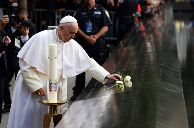 Pope Francis places a white rose on the names of the September 11 victims at the edge of the South Pool of the 9/11 memorial in New York on September 25, 2015. Pope Francis, who has built a wide global following for his reform-minded views, is on a five-day official visit to the US. AFP PHOTO/JEWEL SAMAD