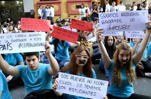 Un grupo de estudiantes de secundaria protesta hoy, jueves 1 de octubre de 2015, frente al Ministerio de Educación y Cultura en Asunción (Paraguay). Estudiantes de colegios públicos y privados de secundaria pidieron hoy en Asunción el fin de la corrupción en el sector educativo y una mayor inversión en formación docente, material escolar e infraestructuras, semanas después de que protagonizarán multitudinarias marchas en todo el país. Varios centenares de estudiantes de entre 13 y 17 años, vestidos con sus uniformes escolares, se concentraron ante la sede del Ministerio de Educación y Cultura (MEC), en el centro de la capital paraguaya, y realizaron una sentada como forma de protesta. La protesta coincidió con la convocatoria de la ministra de Educación, Marta Lafuente, para una reunión entre los estudiantes secundarios y el presidente de Paraguay, Horacio Cartes, el próximo lunes en el Palacio de Gobierno, para "establecer un diálogo amplio de política". EFE/Andrés Cristaldo Benítez