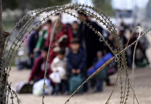 Un grupo de refugiados aguarda tras la alabrada, esperando permiso para cruzar la frontera con Grecia, en Gevgelija, República de Macedonia, hoy 19 de octubre 2015. Miles de migrantes continúan llegando a Macedonia en su camino hacia Europa. Los servicios municipales de la pequeña población de Gevgelija reconocen estar desbordados ante las masivas llegadas. Europa está sufriendo la mayor ola de inmigrantes registrada desde la Segunda Guerra mundial, y se calcula que más de la mitad de los desplazados provienen de Siria. EFE/Georgi Licovski