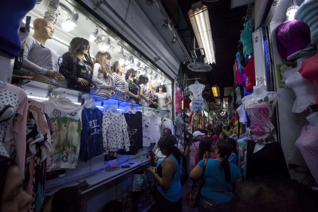 CAR01. CARACAS (VENEZUELA), 16/12/2015.- Fotografía del 15 de diciembre del 2015 de un grupo de personas caminando en un pasillo del mercado popular La Hormiga ubicado en el sur de Caracas (Venezuela). Este año la crisis económica dificulta la fiesta de consumo que supone la navidad en Venezuela, además de los regalos del "niño Jesús", los venezolanos solían gastar en "estrenos" de ropa y calzado, la cena navideña y decoración alusiva a la época, ahora, "el dinero no alcanza". EFE/MIGUEL GUTIÉRREZ