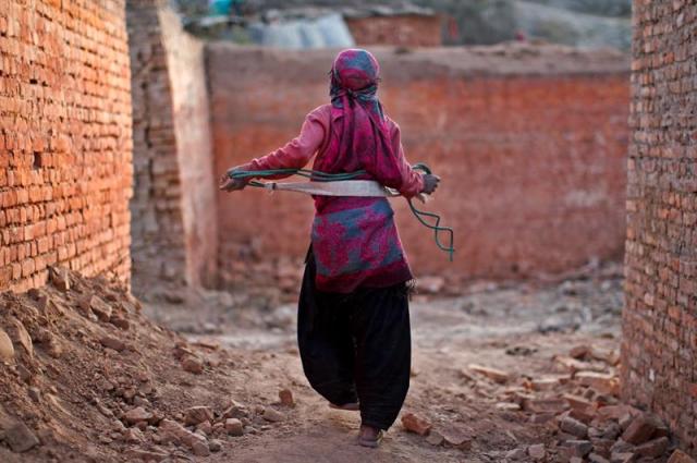 Una joven nepalí regresa a su casa al término de su jornada de trabajo en una fábrica de ladrillos en Lalitpur, Nepal, hoy 21 de diciembre de 2015. Miles de migrantes indios y nepalíes llegan estos días al valle de Katmandú para trabajar en las fábricas de ladrillos, obligados en muchos casos por la pobreza y abandonando la educación, en el caso de los más pequeños. La demanda de ladrillos ha aumentado después de que más de treinta millones de casas resultaron dañadas por el terremoto de abril. EFE/NARENDRA SHRESTHA