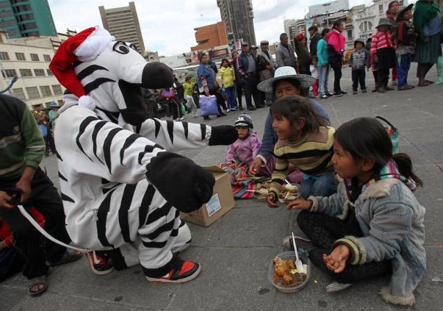 Un educador municipal disfrazado de cebra habla con niños durante un "Apthapi" (en aimara, comida campesina comunitaria que se degusta en grupo) hoy, martes 22 de diciembre de 2015, en La Paz (Bolivia). Centenares de personas, incluidos niños trabajadores, indígenas del altiplano boliviano e indigentes participaron en el acto que fue organizado por la alcaldía de La Paz con motivo del "Día de la Solidaridad" en esta urbe. EFE/MARTIN ALIPAZ