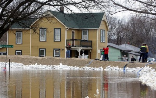 Personas permanecen cerca de un dique de reciente construcción que contiene el aumento del nivel de las aguas del río Mississippi en la localidad de Kimmswick, Missouri, el jueves 31 de diciembre de 2015. Las inundaciones comenzaron a bajar en diversas comunidades afectadas en el centro norte del país, donde centenares de viviendas registraron daños y centenares más fueron evacuadas. (Vía AP Foto/Laurie Skrivan/St. Louis Post-Dispatch)