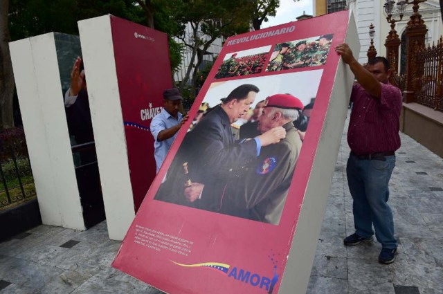 Venezuelan National Assembly employees remove from the building  pictures of late President Hugo Chavez, in Caracas on January 6, 2016. Venezuela's opposition on Tuesday broke the government's 17-year grip on the legislature and vowed to force out President Nicolas Maduro despite failing for the time being to clinch its hoped-for "supermajority." AFP PHOTO/RONALDO SCHEMIDT / AFP / RONALDO SCHEMIDT