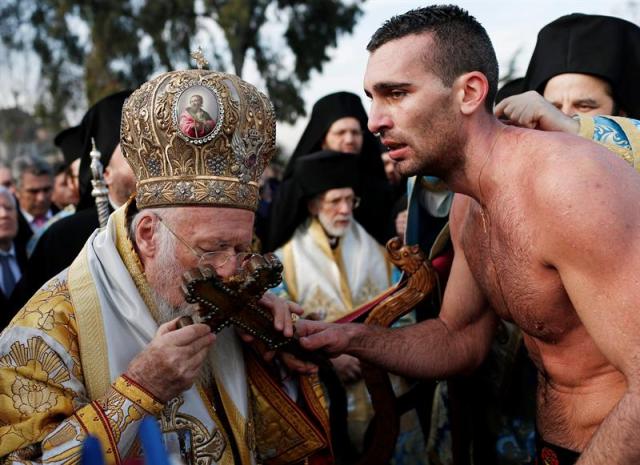 El Patriarca ortodoxo, Bartolomeo I, besa la cruz atrapada por el joven Nicolaos Solis tras lanzarla al agua durante la tradición que se celebra con motivo del día de la Epifanía en Estambul (Turquía) hoy, 6 de enero de 2016. Cada año, nadadores ortodoxos compiten por conseguir la cruz lanzada a aguas del Bósforo. EFE/Sedat Suna