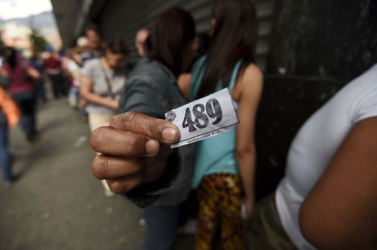 A woman holding a number to buy food waits outside a supermarket in Caracas, Venezuela on January 21, 2016. Trade unions demonstrated Wednesday outside the Venezuelan National Assembly against the economic emergency decrees issued by President Nicolas Maduro, who was meeting with the legislative commission studying whether parliament will approve the executive measures.  AFP PHOTO/JUAN BARRETO / AFP / JUAN BARRETO