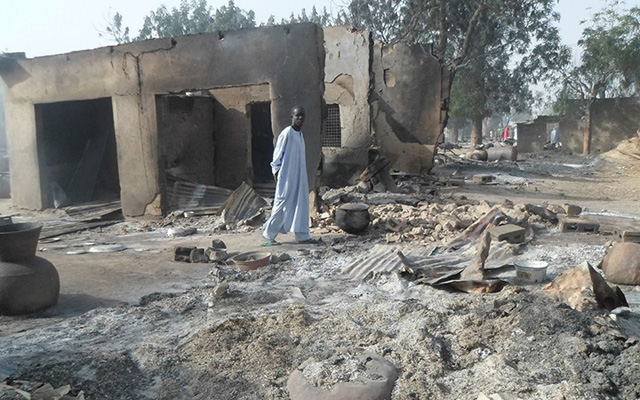 A man walks past burnt out houses following an attack by Boko Haram in Dalori village 5 kilometers (3 miles) from Maiduguri, Nigeria, Sunday Jan. 31, 2016. A survivor hidden in a tree says he watched Boko Haram extremists firebomb huts and listened to the screams of children among people burned to death in the latest attack by Nigeria¿ s homegrown Islamic extremists. (AP Photo/Jossy Ola) Nigeria Boko Haram