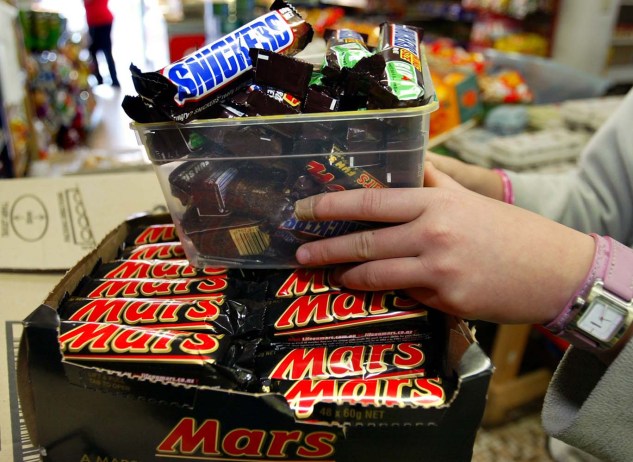 A shopkeeper in removes Mars Bars and Snickers Bars from the shelves of her convenience store in this picture taken on July 2, 2005 in Sydney, Australia. U.S. chocolate maker Mars Inc announced February 23, 2016 a recall of Mars and Snickers bars as well as some other products in Germany on Tuesday after bits of plastic were found in one of its products.  Picture taken July 2, 2005.    REUTERS/Will Burgess/Files