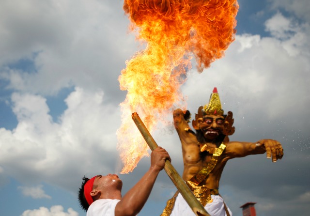 Un hindú balinesa sopla el fuego, durante un desfile llevando efigies Ogoh-ogoh que simbolizan los malos espíritus, durante un ritual antes de Nyepi, el día de silencio, en Palembang, provincia del sur de Sumatra, Indonesia 8 de marzo de 2016. Enggan es un día de silencio para el auto -Reflexión celebrando el nuevo año hindú de Bali, donde las personas pueden no utilizar las luces, encender fuego, trabajo, viajes, ni disfrutar de entretenimiento. REUTERS / Darren Whiteside