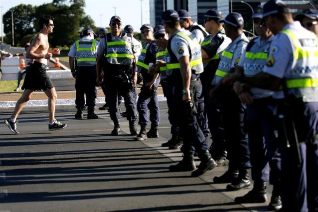 Un hombre pasa frente a la policía brasileña en la avenida Explanada de los Ministerios en Brasilia (Brasil). El simbólico "muro" levantado en el corazón de Basilia para evitar enfrentamientos entre los partidarios de Dilma Rousseff y sus detractores refleja con claridad la fractura social del país ante el proceso destituyente que amenaza a la presidenta. EFE/FERNANDO BIZERRA JR