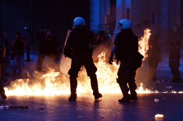 La policía griega custodian las calles en medio de cócteles molotov lanzados por los manifestantes durante una manifestación en contra de paquete de reformas en Atenas el 8 de mayo de 2016. griega policía antidisturbios el domingo lanzó gases lacrimógenos para dispersar a los manifestantes que lanzaron cócteles molotov durante una protesta contra la austeridad fuera del parlamento en Atenas, informaron los medios locales, ya que los legisladores preparan para votar en un impuesto y pensiones polémica reforma. LOUISA GOULIAMAKI / AFP