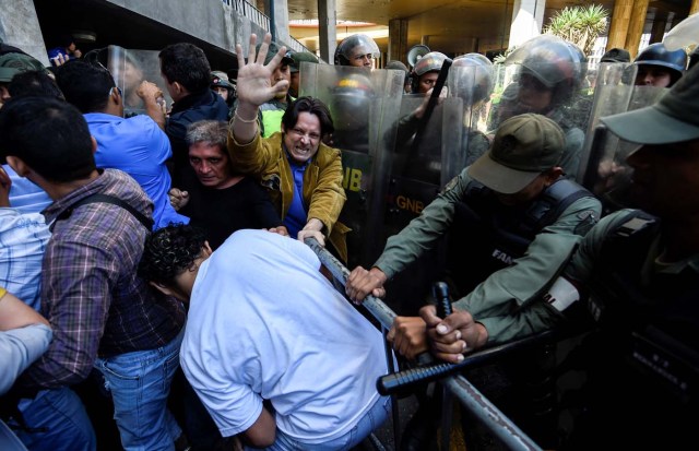 Opponents of Nicolas Maduro's government clash with riot police before the National Electoral Council during a demonstration in Caracas on June 9, 2016. / AFP PHOTO / JUAN BARRETO