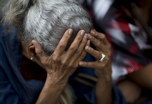 En esta imagen, tomada el 3 de mayo de 2016, una mujer se sostiene la cabeza entre las manos mientras espera en una fila en el exterior de un supermercado para comprar comida, en Caracas, Venezuela. Nueve de cada 10 personas dicen que no pueden comprar alimentos suficientes, de acuerdo con un estudio de la Universidad Simón Bolívar. (AP Foto/Ariana Cubillos)