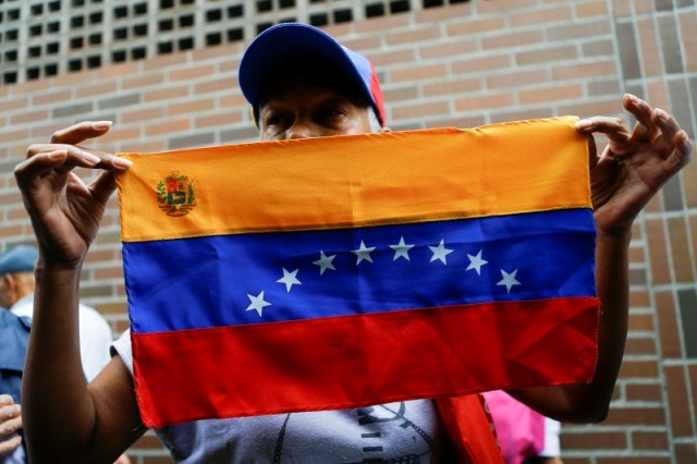 Una mujer sostiene una bandera de Venezuela a las afueras de un centro de validación durante la segunda fase de verificación de firmas para solicitar un referéndum contra el presidente Nicolás Maduro, Caracas, Venezuela, 20 de junio del 2016. Un grupo de venezolanos pedirá en septiembre a Estados Unidos que revise los expedientes migratorios de 89 compatriotas que viven en ese país y que habrían hecho fortunas producto de sus vínculos con los gobiernos socialistas de Hugo Chávez y Nicolás Maduro, dijo un ex juez que lidera la iniciativa. REUTERS/Ivan Alvarado