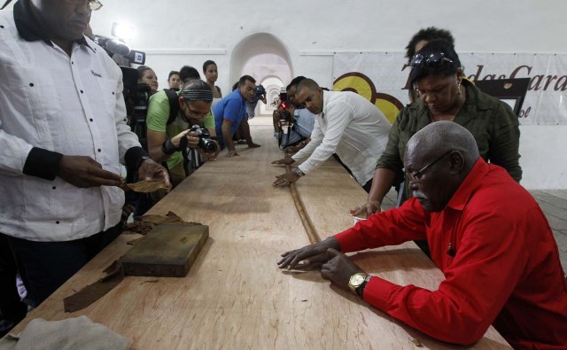 HAB112. LA HABANA (CUBA) 12/08/2016.- José Castelar Cairo, conocido como "Cueto" (d), presentó hoy, viernes 12 de agosto de 2016, en La Habana (Cuba), el puro más grande del mundo en honor al aniversario del líder de la Revolución cubana, Fidel Castro, que mañana cumplirá nueve décadas. Con este puro, "Cueto" rompió su anterior marca de 81,80 metros de largo, establecida en 2011, y así alcanza el sexto récord Guinnes de su carrera al mayor puro del mundo. EFE/Ernesto Mastrascusa