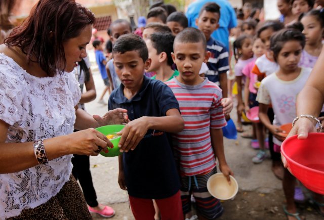 A boy receives a free food which was prepared by residents and volunteers on a street in the low-income neighborhood of Caucaguita in Caracas, Venezuela September 17, 2016. REUTERS/Henry Romero