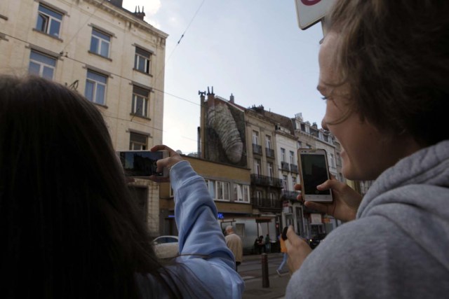 GRA227. BRUSELAS, 23/09/2016.- Dos personas fotografían uno de los grafitis de alto contenido sexual que han aparecido esta semana en Bruselas, entre las que se encuentran un falo circuncidado, la imagen de una penetración, y una vagina en pleno acto de masturbación, que han desbancado al Manneken Pis como el sexo desnudo más célebre de la ciudad. Se desconoce si las obras, que emergen en tan solo una noche, son creadas por un colectivo o por una sola persona, pero una de ellas, la del pene de seis metros de alto y tres de ancho plantada en la comuna de Saint-Gilles, será retirada después de que así lo decidieran los ediles y el propietario del inmueble. Sin embargo, los concejales del distrito centro han acordado mantener intactas las dos obras anónimas y con sesgo femenino que están sometidas a su jurisdicción. EFE/Javier Albisu