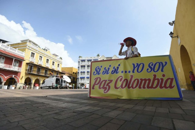 Colombian Paz Colombia Duque, (his name Paz Colombia could be translated as "Peace Colombia"), is photographed in Cartagena, Colombia on September 25, 2016. The placard reads "Yes yes Yes...I Am Paz Colombia". On Monday September 26, 2016 Colombian President Juan Manuel Santos and the leader of the Revolutionary Armed Forces of Colombia (FARC), Rodrigo Londoño - known by his noms de guerre Timoleon Jimenez or Timoshenko - will officially sign a peace agreement in the Cartagena Convention Center to end an armed conflict that has bled the country for over half a century. / AFP PHOTO / LUIS ROBAYO