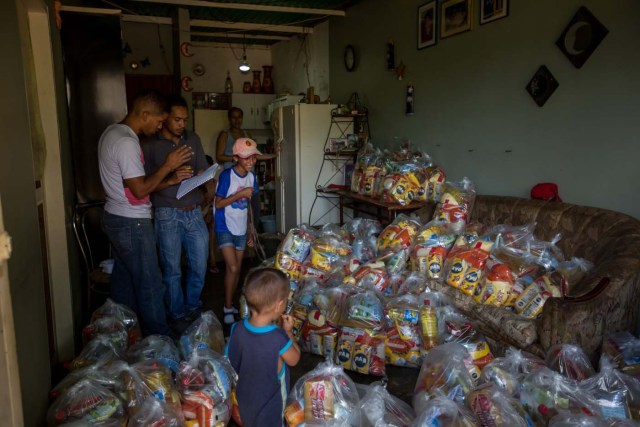 ACOMPAÑA CRÓNICA: VENEZUELA ALIMENTOS - CAR01. CARACAS (VENEZUELA), 28/08/2016.- Fotografía del 20 de agosto del 2016, donde se observan un operativo de entrega de bolsas de comida a habitantes de un barrio del km 3 del Junquito por parte Comités Locales de Abastecimiento y Producción (CLAP) en Caracas (Venezuela). La severa escasez de productos básicos en Venezuela ha llevado a que la foto diaria del país sea una inmensa fila frente a muchos abastos y supermercados, un problema que el Gobierno intenta solucionar con un sistema de venta de alimentos, conformado solo por militantes chavistas, conocido como CLAP. EFE/MIGUEL GUTIÉRREZ