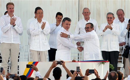 En esta imagen, tomada el 26 de septiembre de 2016, el presidente de Colombia, Juan Manuel Santos (delante, izquierda) y el líder de las Fuerzas Armadas Revolucionarias de Colombia, Rodrigo Londoño, conocido por el alias Timochenko, se dan la mano tras firmar el acuerdo de paz entre el gobierno colombiano y las FARC para terminar con más de 50 años de conflicto, en Cartagena, Colombia. Detrás, de izquierda a derecha: el ministro de Exteriores de Noruega, Borge Brende; el secretario general de Naciones Unidas, Ban Ki Moon; el presidente de México, Enrique Peña Nieto; el presidente de Perú, Pedro Pablo Kuczynski; el presidente de Cuba, Raúl Castro y el rey emérito de España, Juan Carlos I. (AP Foto/Fernando Vergara)