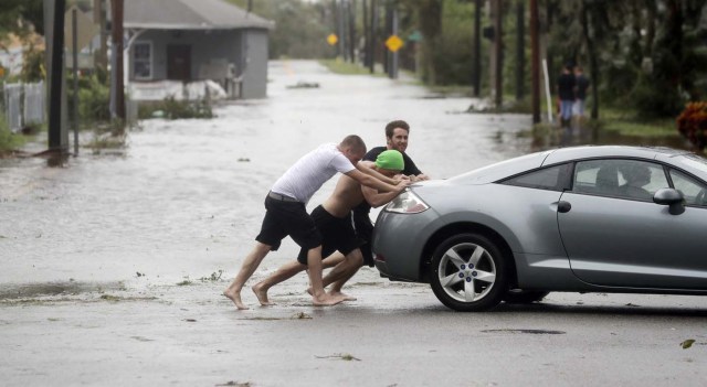 Noah Simons conduce su auto mientras es empujado para salir de las calles inundadas a causa del huracán Matthew el viernes 7 de octubre de 2016 en Daytona Beach, Florida. La tormenta evitó el tramo más poblado de la costa de Florida de un un impacto catastrófico el viernes, pero amenazó algunas de las ciudades más históricas y pintorescas del sur con grandes inundaciones y fuertes vientos en su paso por la línea costera. (AP Foto/Eric Gay)