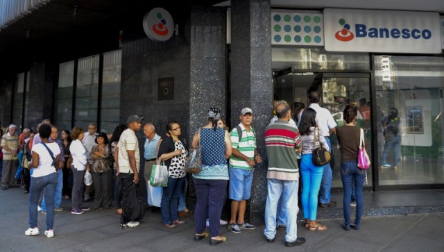 People queue outside a bank in Caracas in an attempt to deposit money, on December 13, 2016. Venezuelan President Nicolas Maduro ordered on December 12 the border with Colombia sealed for 72 hours, accusing US-backed "mafias" of conspiring to destabilize his country's economy by hoarding bank notes. The closure came a day after Maduro signed an emergency decree removing Venezuela's largest bank note, the 100 bolivar bill, from circulation because of what he called a Washington-sponsored plot against his country's troubled economy. / AFP PHOTO / FEDERICO PARRA