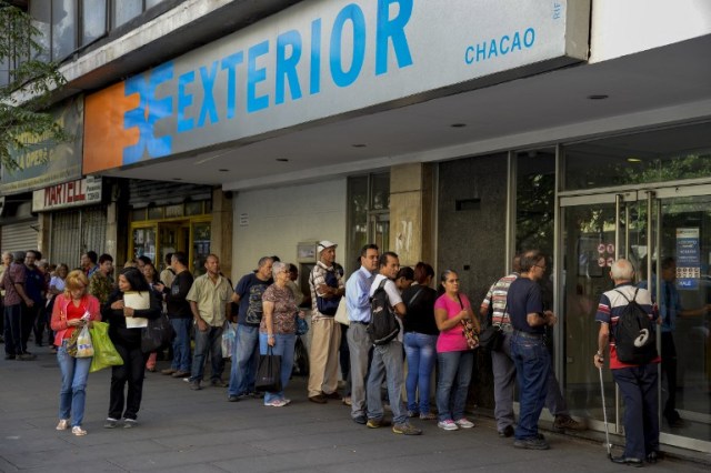 People queue outside a bank in Caracas in an attempt to deposit money, on December 13, 2016. Venezuelan President Nicolas Maduro ordered on December 12 the border with Colombia sealed for 72 hours, accusing US-backed "mafias" of conspiring to destabilize his country's economy by hoarding bank notes. The closure came a day after Maduro signed an emergency decree removing Venezuela's largest bank note, the 100 bolivar bill, from circulation because of what he called a Washington-sponsored plot against his country's troubled economy. / AFP PHOTO / FEDERICO PARRA