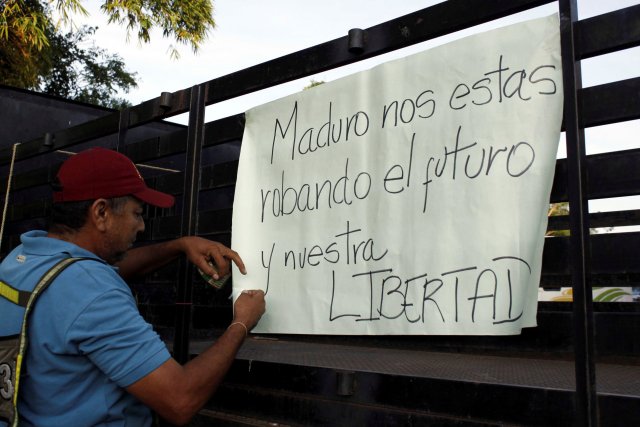 A man places a placard on a truck during a protest due to a lack of cash in El Pinal