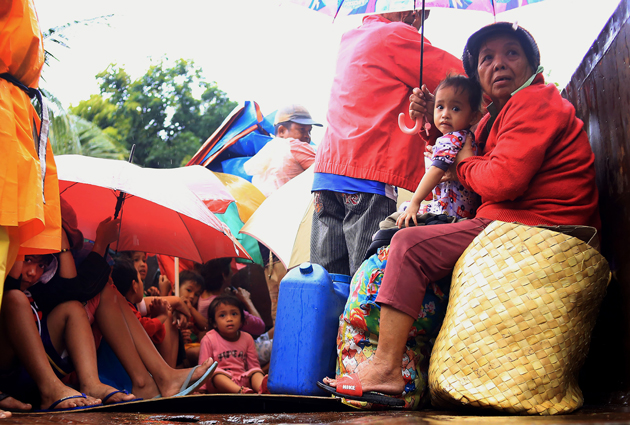 Residents sit in a truck after the local government implemented preemptive evacuations at Barangay Matnog, Daraga, Albay province on December 25, 2016, due to the approaching typhoon Nock-Ten. Babies, toddlers and old people were loaded onto military trucks in the Philippines on December 25 as thousands fled from the path of a powerful typhoon barrelling towards the disaster-prone archipelago. / AFP PHOTO