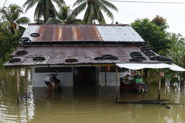 A man inspects his motorbike after riding through floodwaters in Jal Besar, Malaysia's northeastern town of Tumpat, which borders with Thailand, on January 6, 2017. Serious flooding in Malaysia's northeast states for almost a week is showing some respite but has damaged homes, caused loss of income and disrupted schooling, victims said on January 6. / AFP PHOTO / Mohd RASFAN