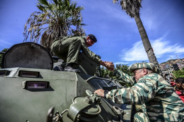 Venezuelan lawmaker Diosdado Cabello (R) mounts in an armoured tank during a demonstration in Caracas on January 14, 2017. / AFP PHOTO / JUAN BARRETO