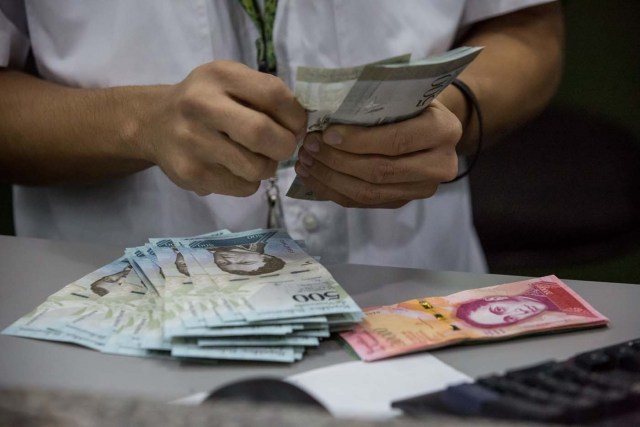 CAR01. CARACAS (VENEZUELA), 16/01/2017.- Trabajadores de un banco manipulan billetes del nuevo cono monetario hoy 16 de enero de 2017, en Caracas (Venezuela). Los billetes de 500, 5.000 y 20.000 bolívares, tres de las seis piezas que conforman el nuevo cono monetario, comenzaron a circular hoy en Venezuela tal y como lo aseguró ayer el presidente, Nicolás Maduro, y un mes más tarde de lo previsto inicialmente debido a un "sabotaje internacional". EFE/Miguel Gutiérrez