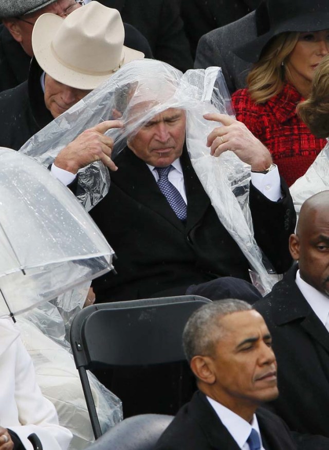 Former President George W. Bush keeps covered under the rain during the inauguration ceremonies swearing in Donald Trump as the 45th president of the United States on the West front of the U.S. Capitol in Washington, U.S., January 20, 2017. REUTERS/Rick Wilking