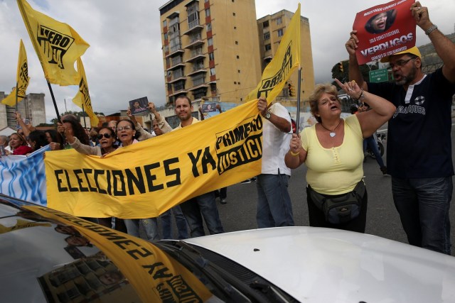 Opposition supporters hold a placard that reads "Elections now" as they shout slogans during a protest against Venezuelan President Nicolas Maduro's government outside the Supreme Court of Justice (TSJ) in Caracas, Venezuela February 9, 2017. REUTERS/Carlos Garcia Rawlins